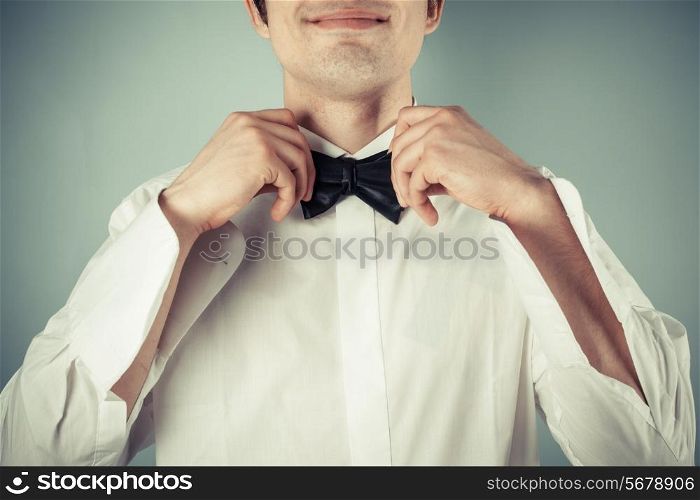 Closeup on a happy young man tying a bow tie
