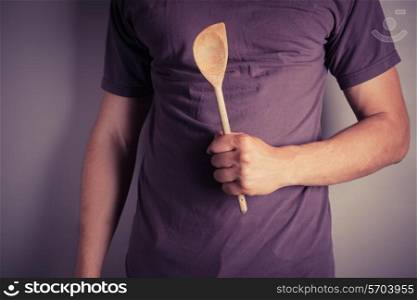 Closeup on a man holding a wooden spoon