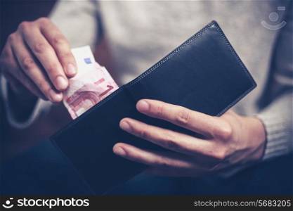 Closeup on a man&rsquo;s hands as he is getting a banknote out of his wallet