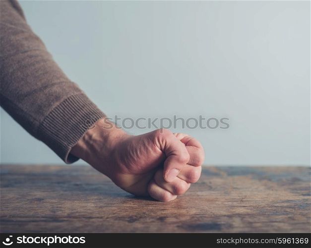 Closeup on a man slamming his fist on a wooden table