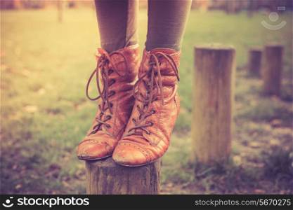Closeup on a woman&rsquo;s feet as she is balancing on a wooden post in the park