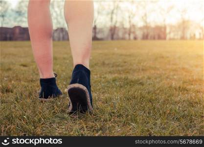 Closeup on a woman&rsquo;s feet as she is walking in the park on the grass
