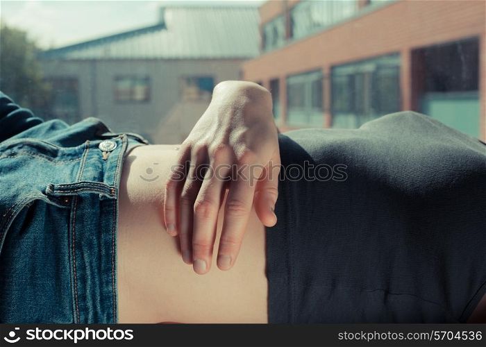 Closeup on a woman&rsquo;s hand and stomach as she is relaxing by a window
