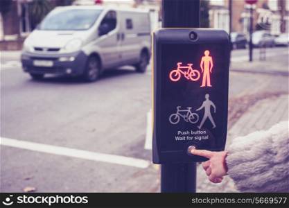 Closeup on a woman&rsquo;s hand as she is pushing a button at pedestrian crossing