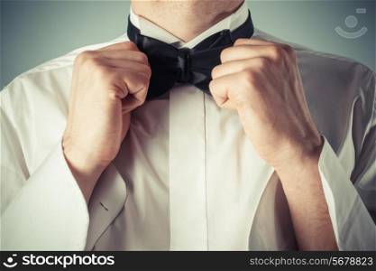 Closeup on a young man as he is tying a bow tie
