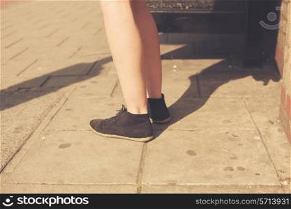 Closeup on a young woman&rsquo;s feet as she is standing in the street on a sunny day