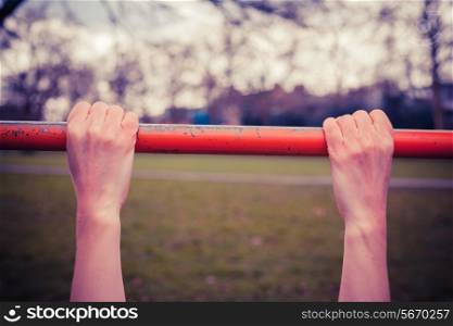 Closeup on a young woman&rsquo;s hands as she is hanging from a monkey bar in the park