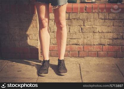 Closeup on a young woman&rsquo;s legs as she is standing in the street on a sunny day