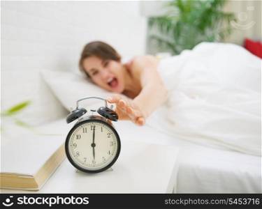 Closeup on alarm clock and angry woman in background