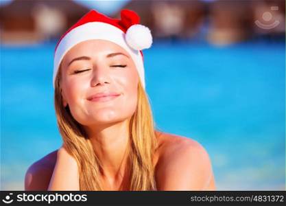 Closeup on attractive female with closed eyes enjoying warm sunny day, wearing red Santa hat, celebrating New Year holidays on Maldive islands&#xA;
