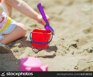Closeup on baby girl playing with bucket and shovel on beach