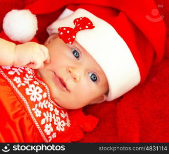 Closeup on beautiful newborn baby wearing red festive Christmas costume, Santa hat with decorative bow, New Year celebration