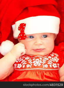 Closeup on beautiful newborn baby wearing red festive Christmas costume, Santa hat with decorative bow, New Year celebration