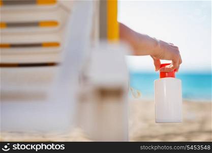 Closeup on bottle of sun screen in hand of female laying on sunbed