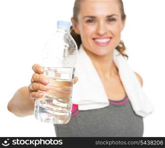 Closeup on bottle of water in hand of smiling fitness young woman