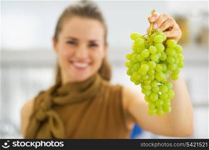 Closeup on branch of grapes in hand of smiling young woman