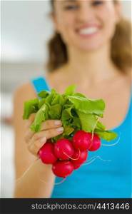 Closeup on bunch of radishes in hand of young woman