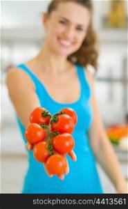 Closeup on bunch of tomato in hand of smiling young woman