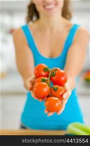 Closeup on bunch of tomato in hand of young woman