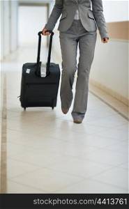 Closeup on business woman walking with wheel bag