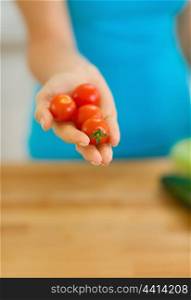 Closeup on cherry tomato in hand of young woman