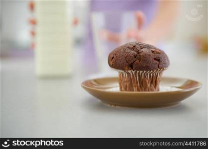 Closeup on chocolate muffin and teenager girl with milk in background
