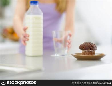 Closeup on chocolate muffin and teenager girl with milk in background