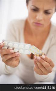 Closeup on concerned young woman studying pills