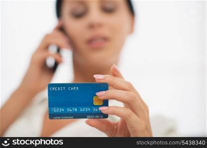 Closeup on credit card in hand of female speaking mobile