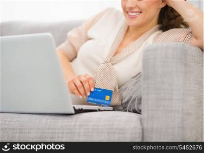 Closeup on credit card in hand of smiling woman with laptop