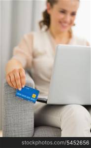 Closeup on credit card in hand of woman using laptop