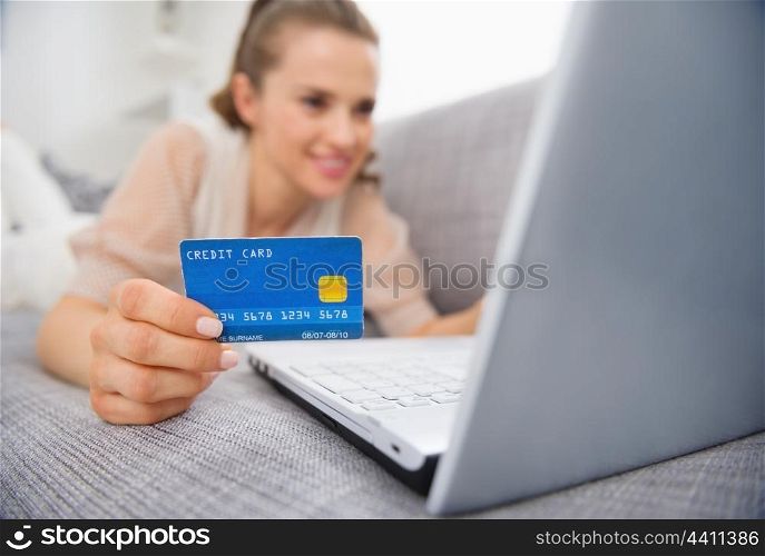 Closeup on credit card in hand of young woman laying on couch