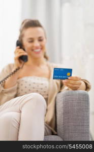 Closeup on credit card in hand of young woman talking phone