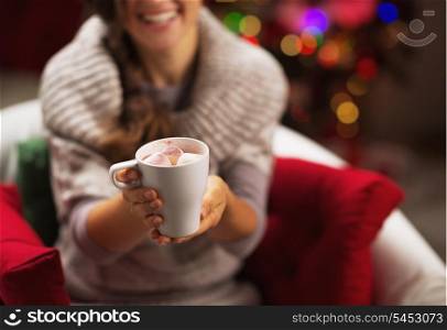 Closeup on cup of hot chocolate with marshmallow in hand of smiling young woman