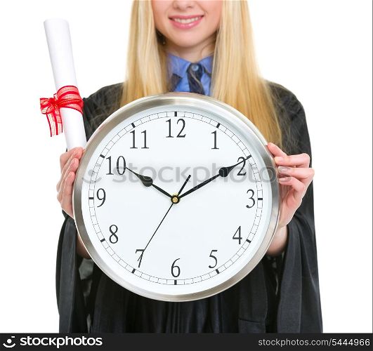 Closeup on diploma and clock in hand of woman in graduation gown