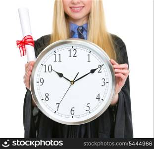 Closeup on diploma and clock in hand of woman in graduation gown