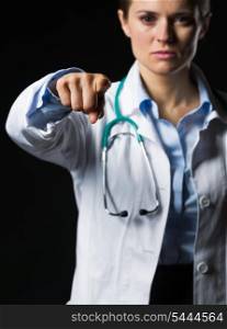 Closeup on doctor woman pointing in camera isolated on black