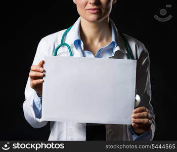 Closeup on doctor woman showing blank paper sheet isolated on black