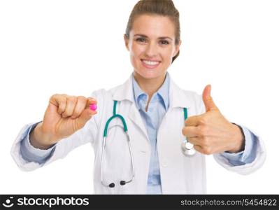 Closeup on doctor woman showing pill and thumbs up