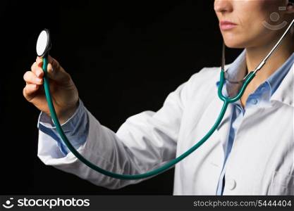 Closeup on doctor woman using stethoscope isolated on black