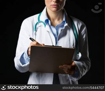 Closeup on doctor woman writing in clipboard isolated on black