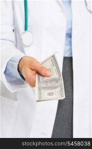Closeup on dollars in hand of doctor woman