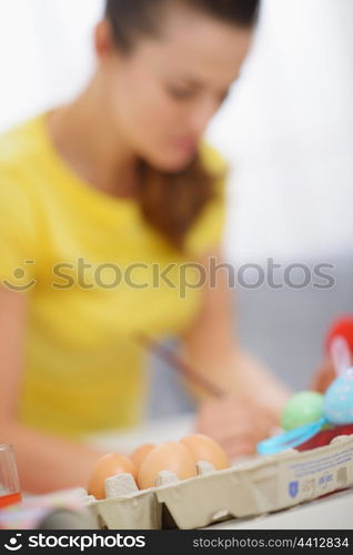 Closeup on eggs and woman making decoration to Easter in background