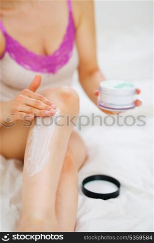 Closeup on female hand applying creme on leg