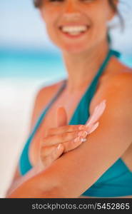 Closeup on female hand applying sun block creme on arm