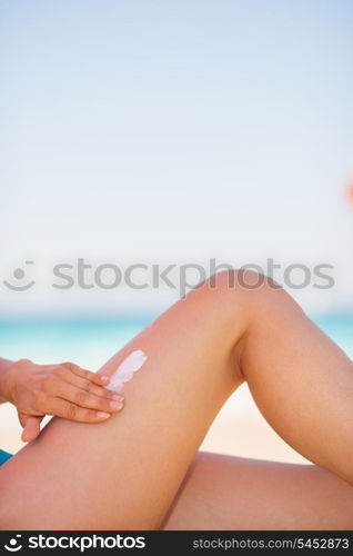 Closeup on female hand applying sun block creme on leg