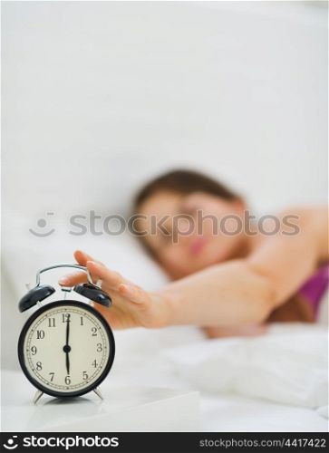 Closeup on female hand reaching to turn off alarm clock