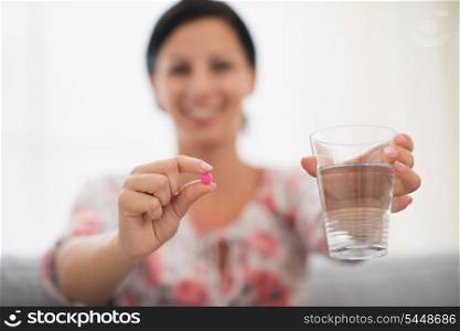 Closeup on female hands holding pink tablet and glass of water