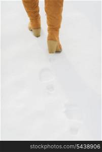 Closeup on female legs in winter boots walking on snow