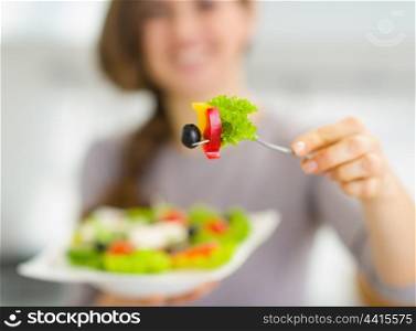 Closeup on fork with salad in hand of young woman